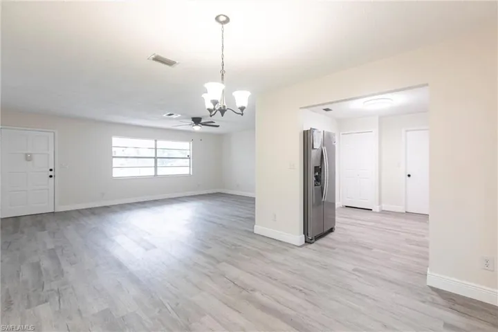 Spare room featuring a chandelier, light wood-type flooring, and a ceiling fan