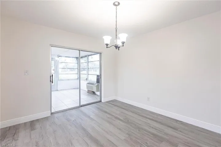Spare room with wood finished floors and a chandelier