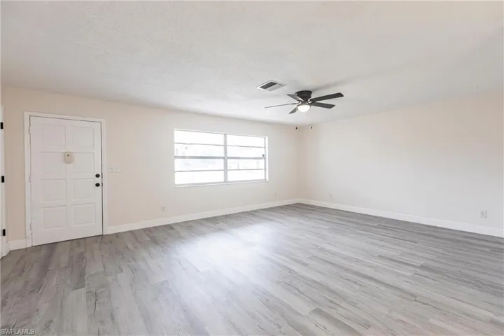 Spare room with wood finished floors, ceiling fan, and a textured ceiling