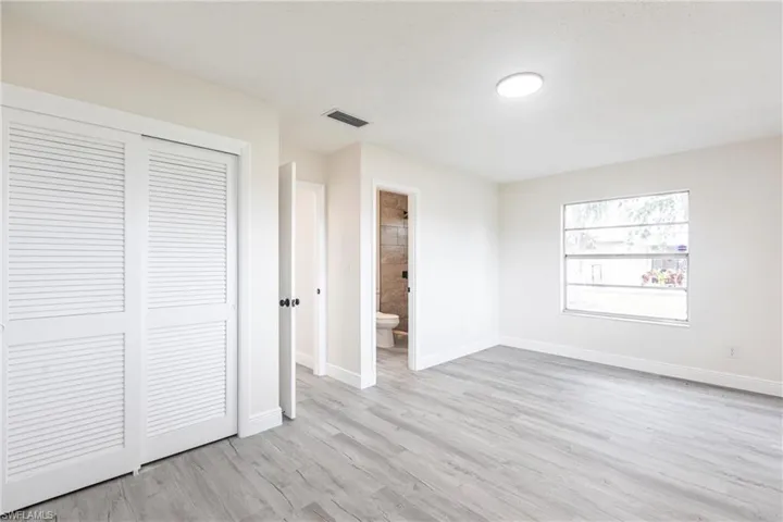 Unfurnished bedroom with a closet, light wood-type flooring, and connected bathroom