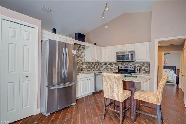 Kitchen featuring appliances with stainless steel finishes, white cabinetry, decorative backsplash, and visible vents