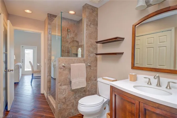 Bathroom with recessed lighting, vanity, toilet, a stall shower, and wood finished floors