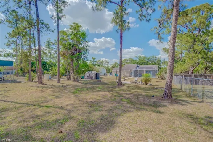 View of yard featuring fence and glass enclosure