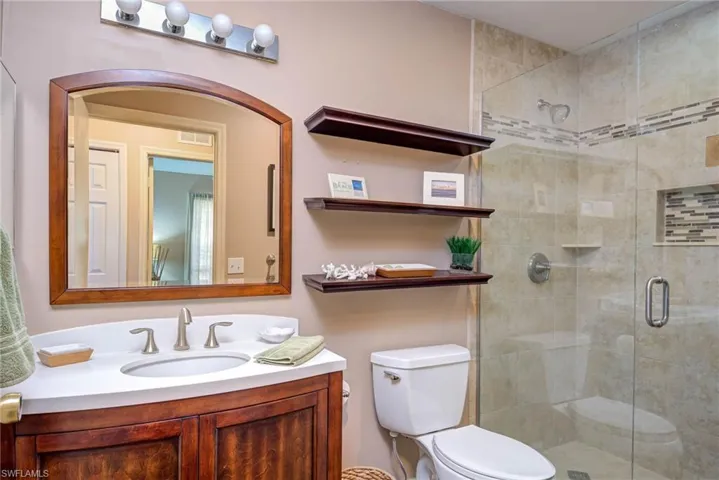 Full bathroom with visible vents, a stall shower, toilet, and vanity