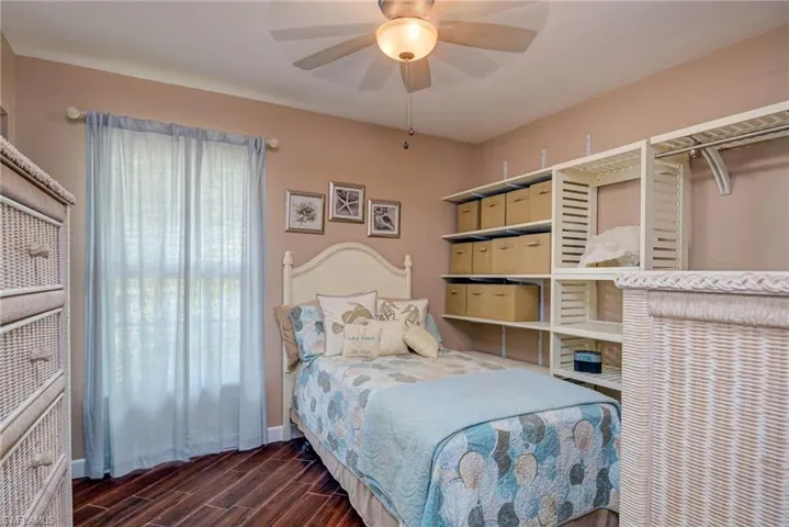 Bedroom with a ceiling fan, dark wood finished floors, and baseboards