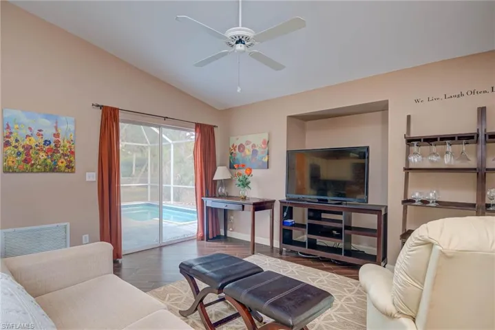 Living area featuring wood finished floors, ceiling fan, baseboards, visible vents, and lofted ceiling