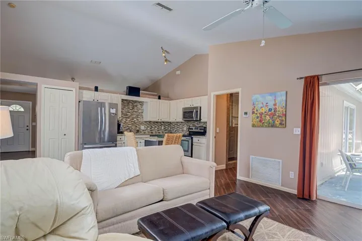 Living area with baseboards, visible vents, a ceiling fan, and dark wood-type flooring