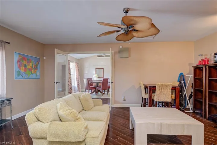 Living area featuring dark wood finished floors, baseboards, and a ceiling fan