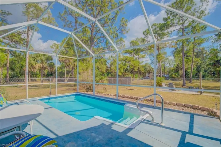 Pool featuring fence, glass enclosure, a yard, and a patio area
