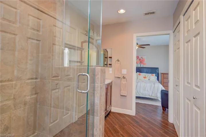 Ensuite bathroom with connected bathroom, vanity, a stall shower, a ceiling fan, and visible vents