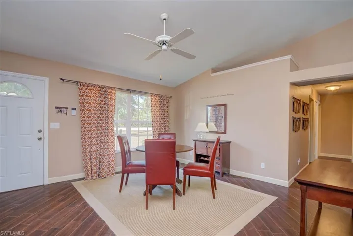 Dining area with dark wood-style floors, ceiling fan, lofted ceiling, and baseboards