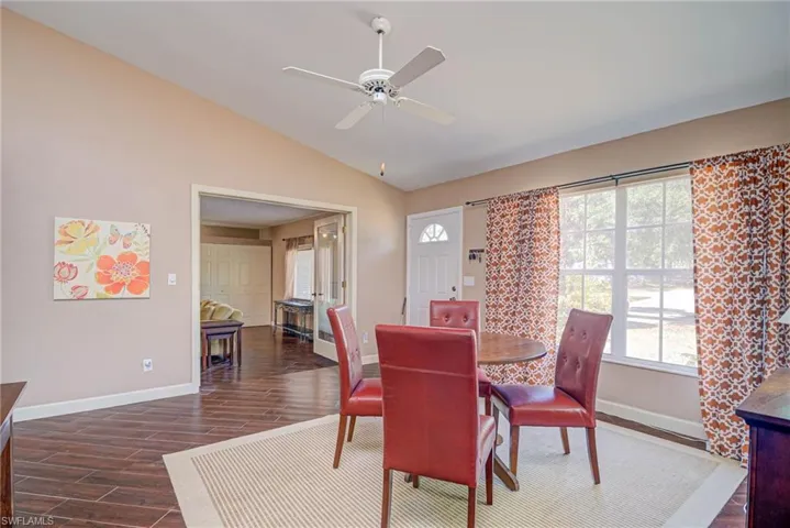 Dining room with baseboards, ceiling fan, dark wood-style flooring, and vaulted ceiling