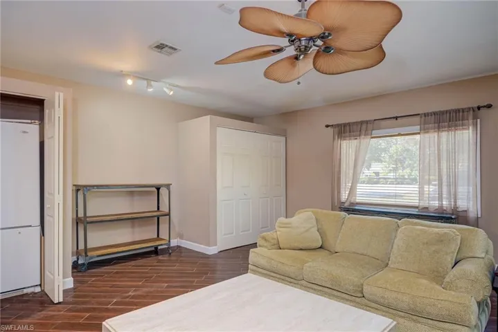 Living area with baseboards, visible vents, a ceiling fan, and dark wood-style flooring