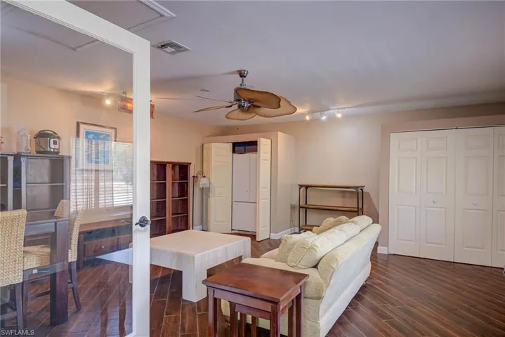 Living room featuring attic access, visible vents, a ceiling fan, and dark wood-style floors