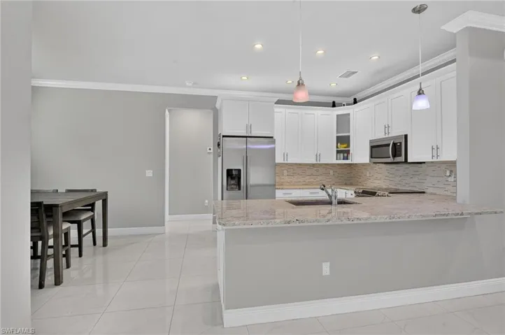 Contemporary kitchen with white cabinetry, stainless steel appliances, granite countertops, and a mosaic tile backsplash