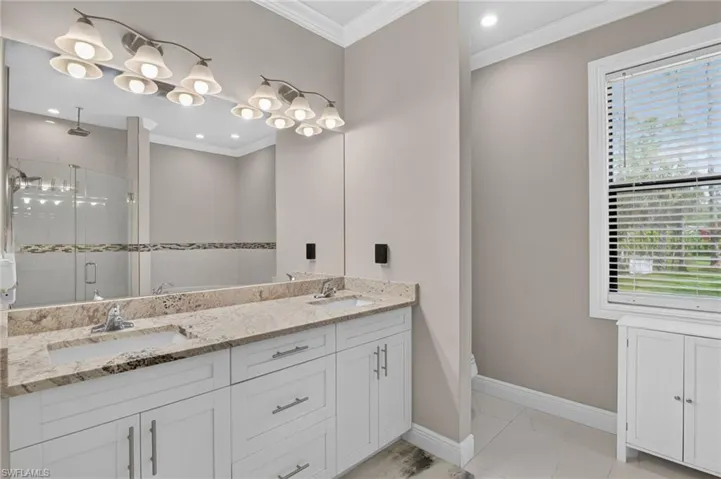 Dual vanity with integrated sinks, granite countertop, and white cabinetry