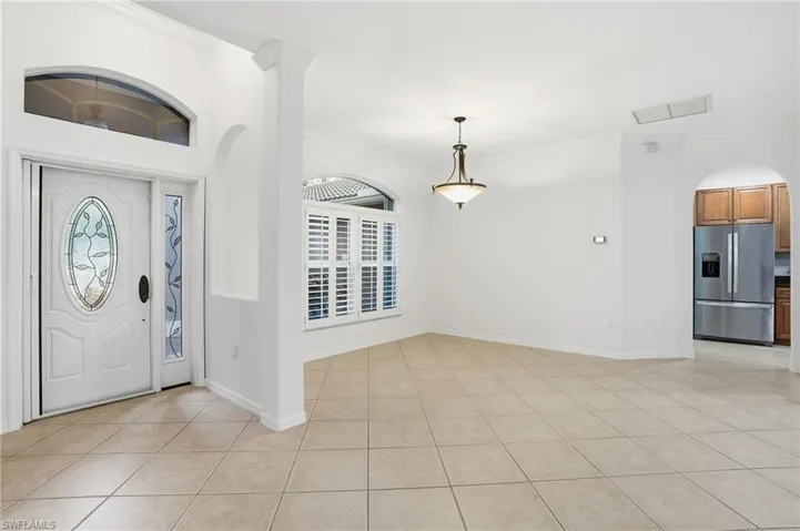 Entrance foyer with arched walkways, ornamental molding, light tile patterned flooring, and healthy amount of natural light