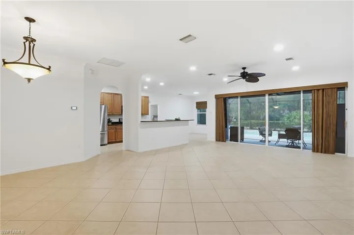 Living room with ceiling fan, ornamental molding, light tile patterned flooring, recessed lighting, and arched walkways