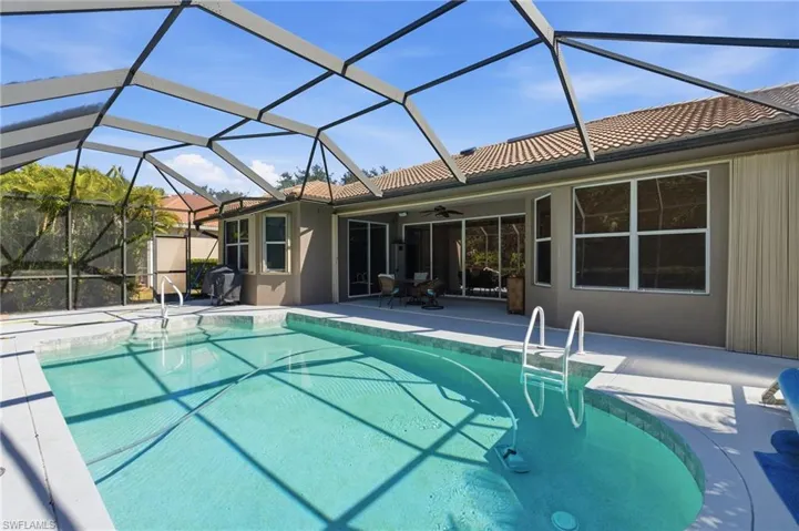 Swimming pool with glass enclosure, a patio area, and a sunroom