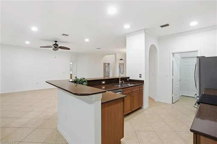 Kitchen featuring light tile patterned floors, a peninsula, arched walkways, a ceiling fan, and recessed lighting