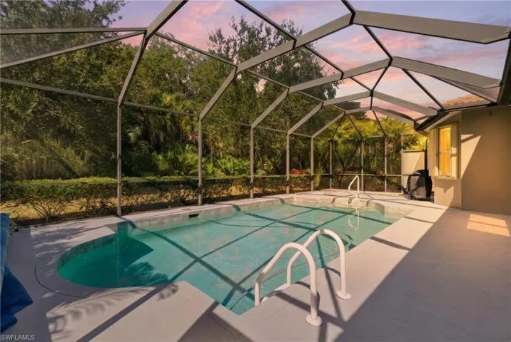 Pool at dusk featuring an outdoor pool, glass enclosure, a patio, and a sunroom