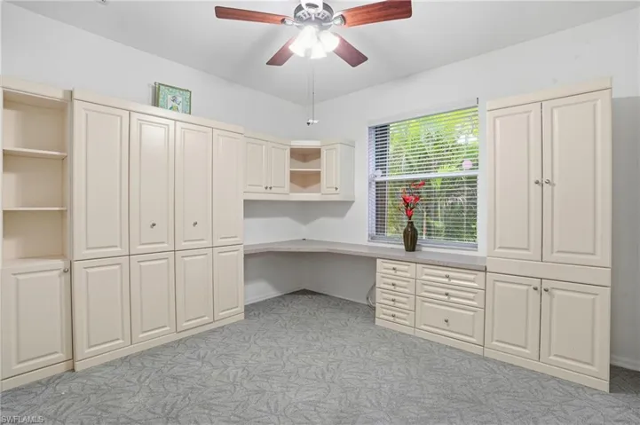 Bedroom 2 with built-in cabinets and Murphy bed, ceiling fan, and light colored carpet