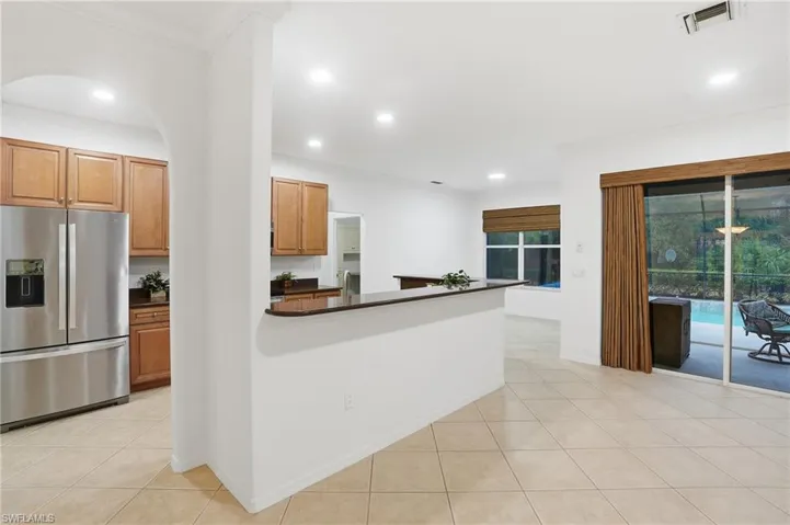 Kitchen featuring stainless steel fridge, light tile patterned floors, recessed lighting, crown molding, and wood finish cabinetry