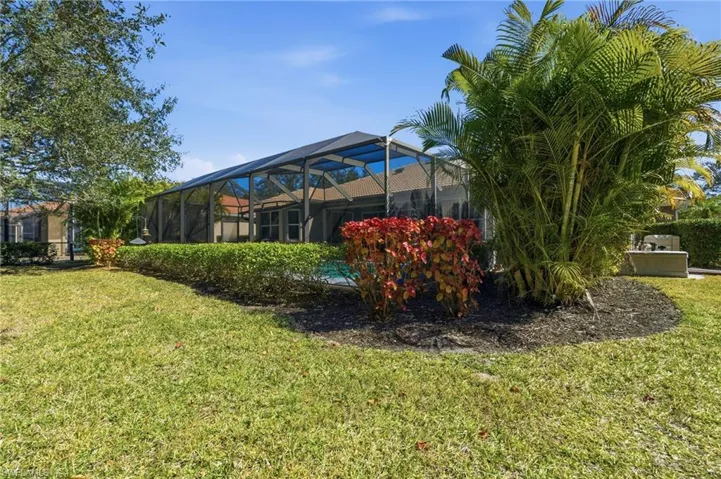 View of grassy yard with a sunroom and a lanai