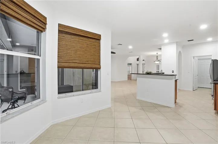 Kitchen featuring light tile patterned floors, arched walkways, ornamental molding, hanging light fixtures, and freestanding refrigerator
