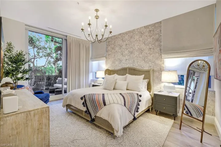 Master bedroom featuring a king bed, tastefully wallpapered walls, a chandelier, light wood-style floors, and access to exterior