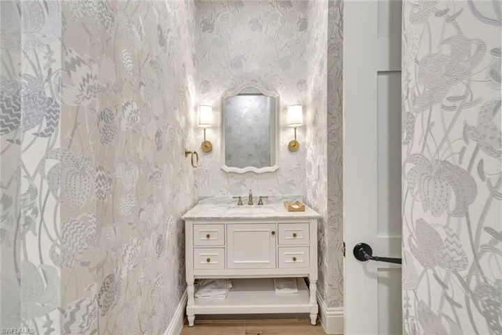 Half bathroom featuring vanity and wallpapered walls