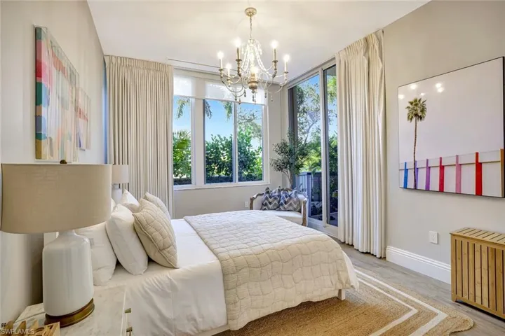 Secondary bedroom with hanging lights, wood finished floors, and access to outside through the private lanai