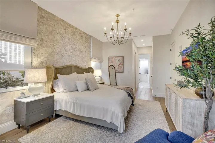 Master bedroom with suspended lighting, light wood-style flooring, wallpapered walls, and multiple windows