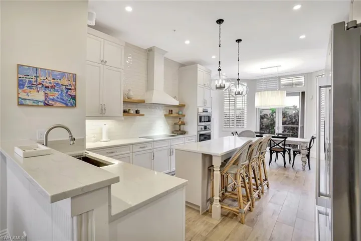 Large kitchen featuring a center island, a kitchen breakfast bar, a wine cellar, stainless steel appliances, light stone countertops, and light wood-style floors