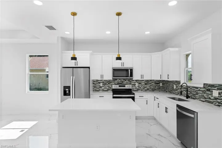 Kitchen with stainless steel appliances, a healthy amount of sunlight, sink, and light tile patterned floors