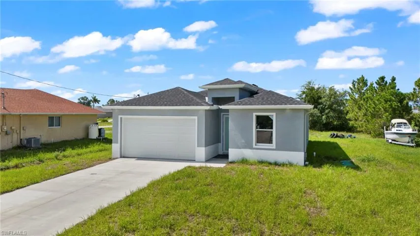 View of front facade featuring a garage, central AC, and a front lawn