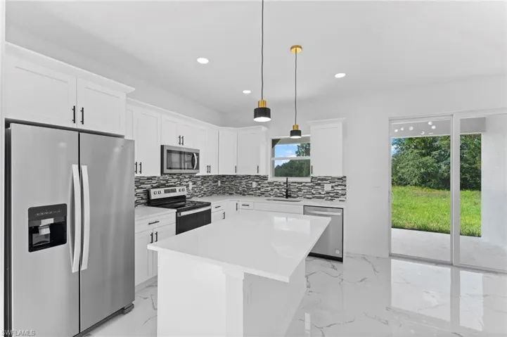 Kitchen with stainless steel appliances, backsplash, a center island, and pendant lighting