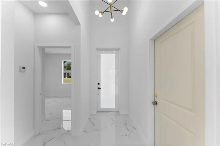 Tiled entryway featuring a notable chandelier