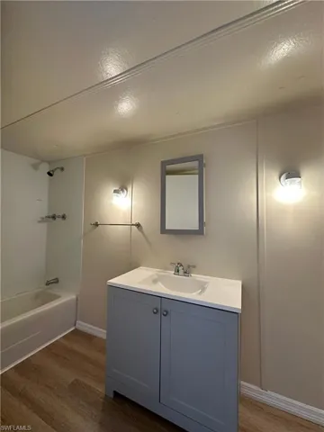 Full bath with vanity, dark wood-type flooring, washtub / shower combination, and a textured ceiling