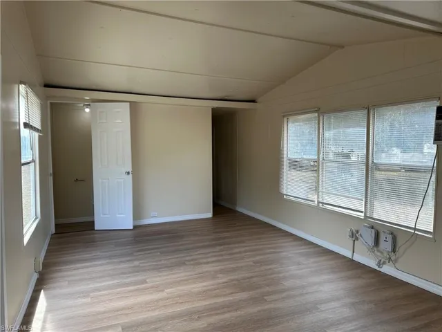 Unfurnished room with vaulted ceiling and light wood-type flooring