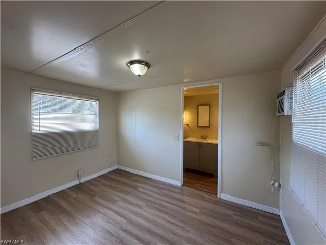 Unfurnished bedroom featuring light wood-type flooring, multiple windows, and ensuite bath