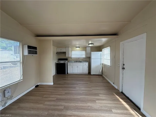 Kitchen with white cabinetry, light countertops, freestanding refrigerator, range with electric cooktop, and light wood-style floors