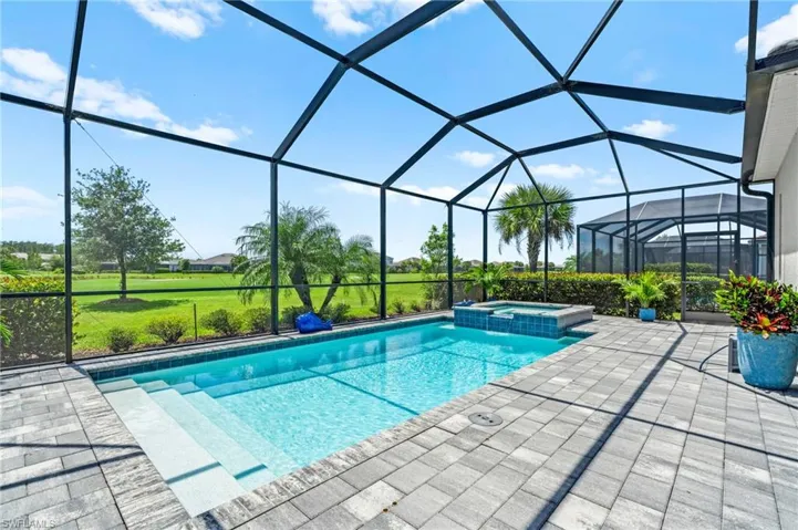 View of pool featuring a lanai, a yard, a patio area, and a pool with connected hot tub