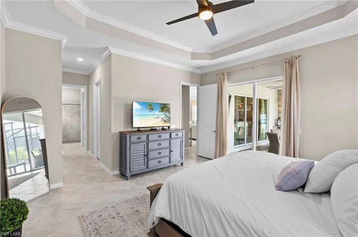 Bedroom with a tray ceiling, access to exterior, crown molding, and light tile patterned flooring