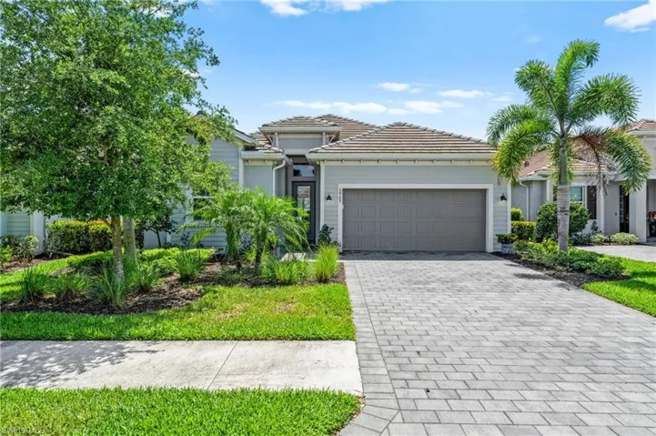 View of front of property featuring a garage, stucco siding, a tiled roof, and decorative driveway
