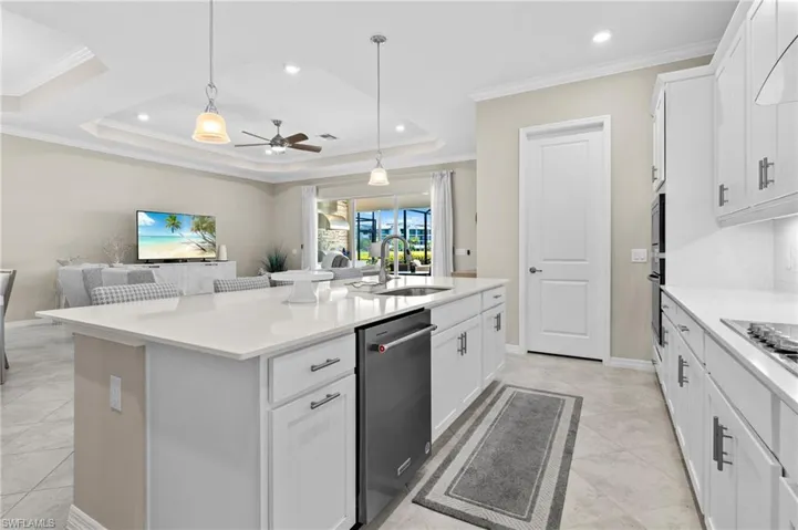 Kitchen featuring open floor plan, a center island with sink, ceiling fan, dishwasher, and a sink