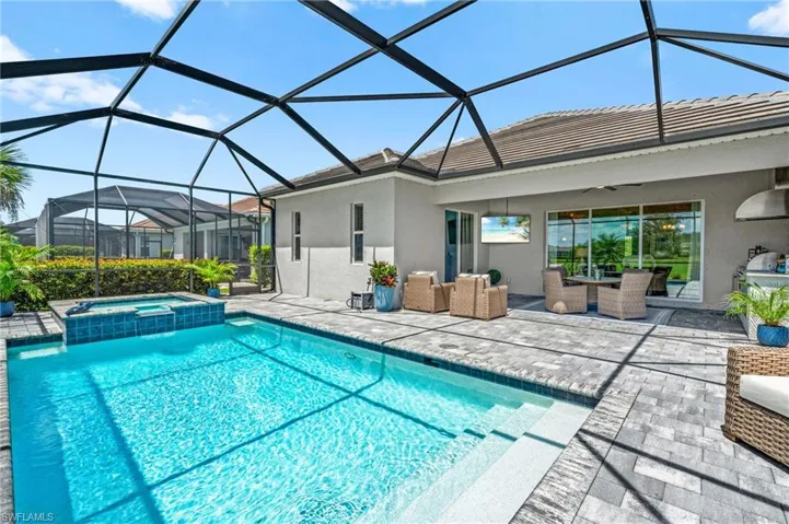 View of swimming pool with a patio, ceiling fan, a pool with connected hot tub, and glass enclosure