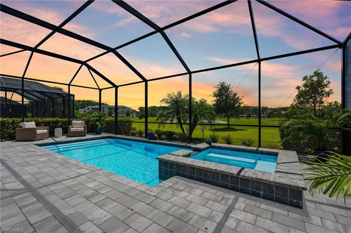 View of pool featuring a patio, a pool with connected hot tub, and glass enclosure