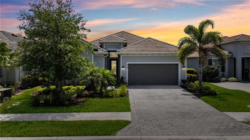 View of front facade featuring a tiled roof, decorative driveway, and an attached garage