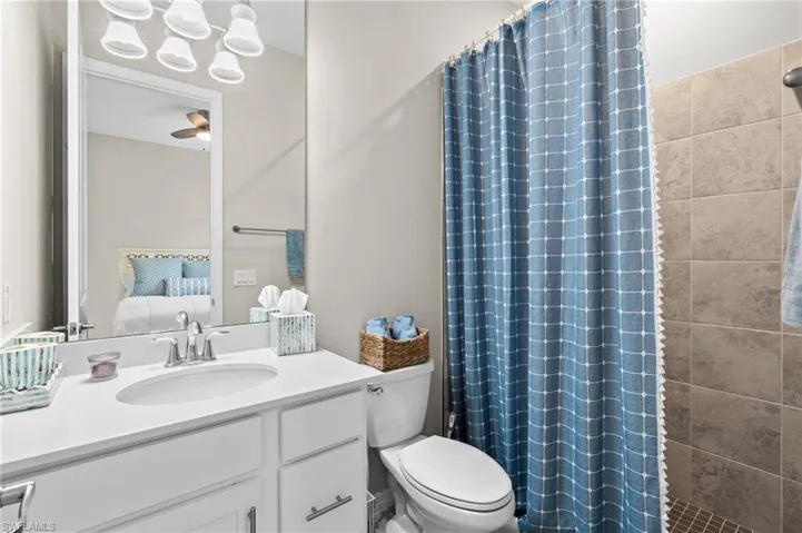 Ensuite bathroom featuring toilet, a ceiling fan, ensuite bath, and a shower with curtain